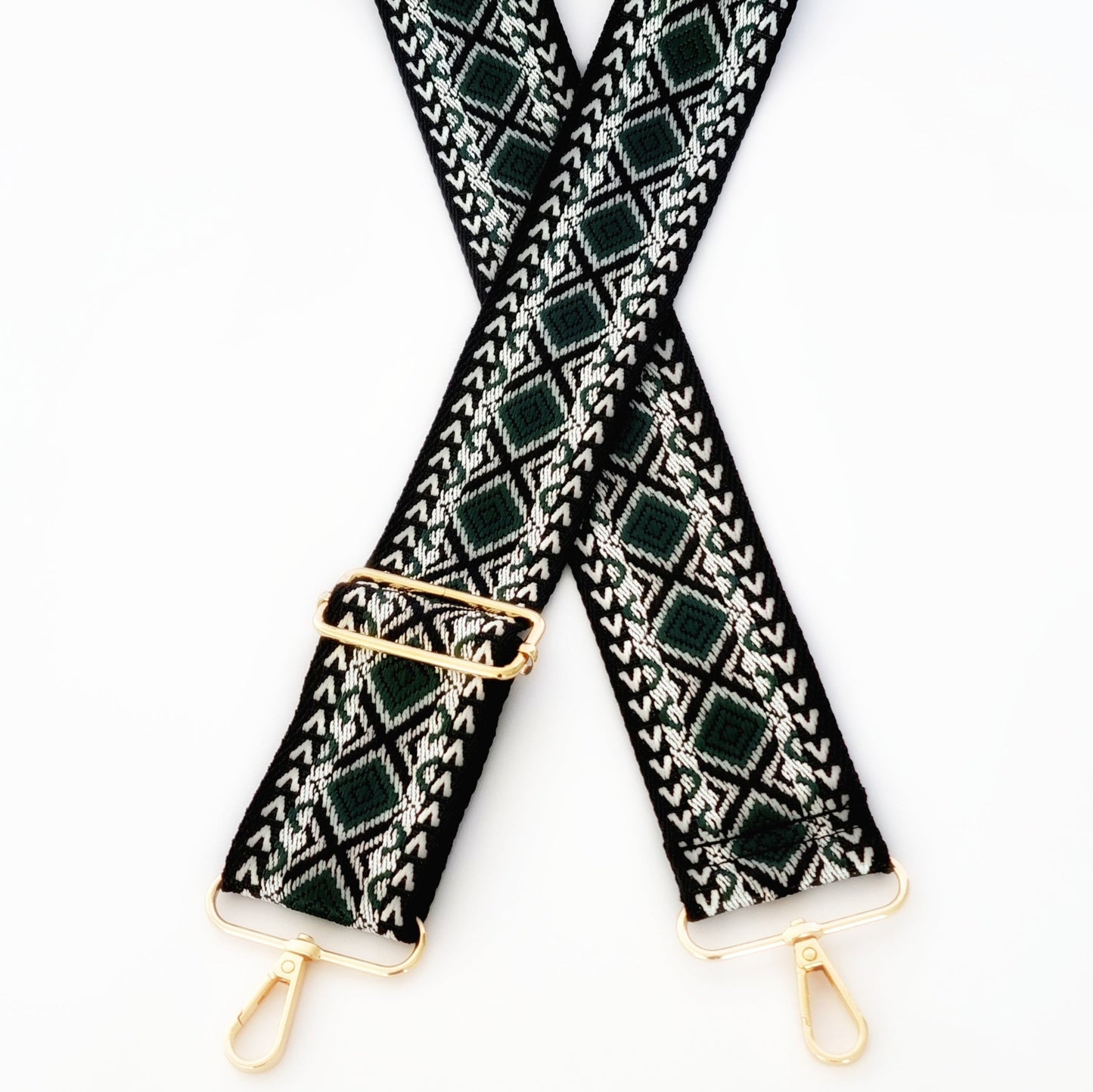 A black and green geometric patterned woven fabric strap with gold hardware for bags.