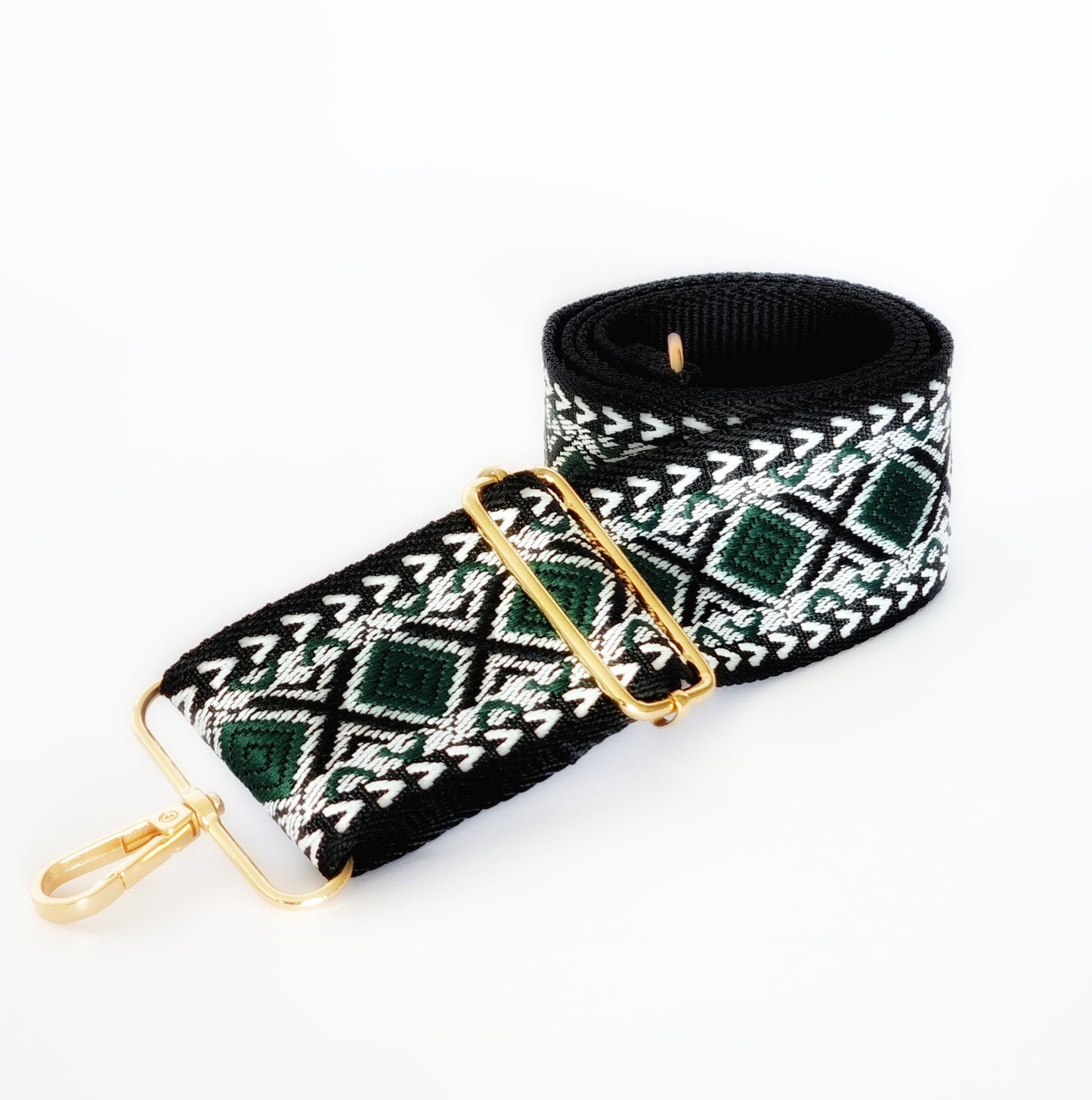 A black and green geometric patterned woven fabric strap with gold hardware for bags.
