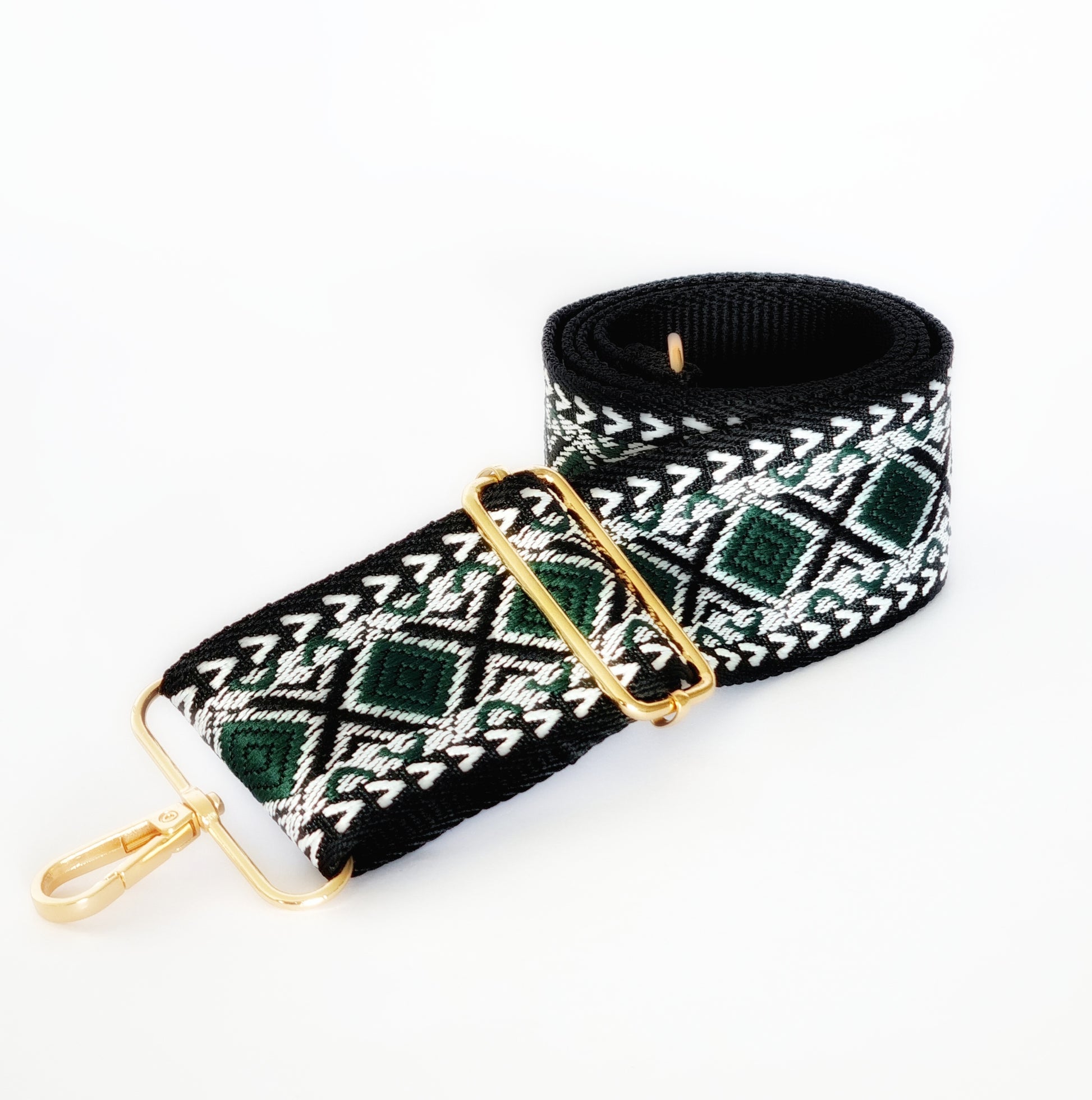 A black and green geometric patterned woven fabric strap with gold hardware for bags.