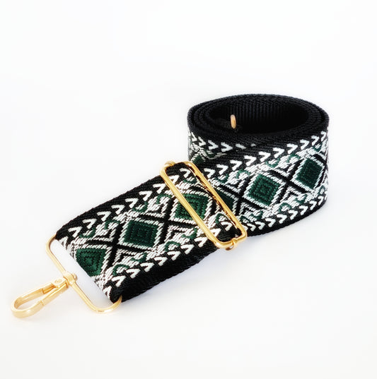 A black and green geometric patterned woven fabric strap with gold hardware for bags.
