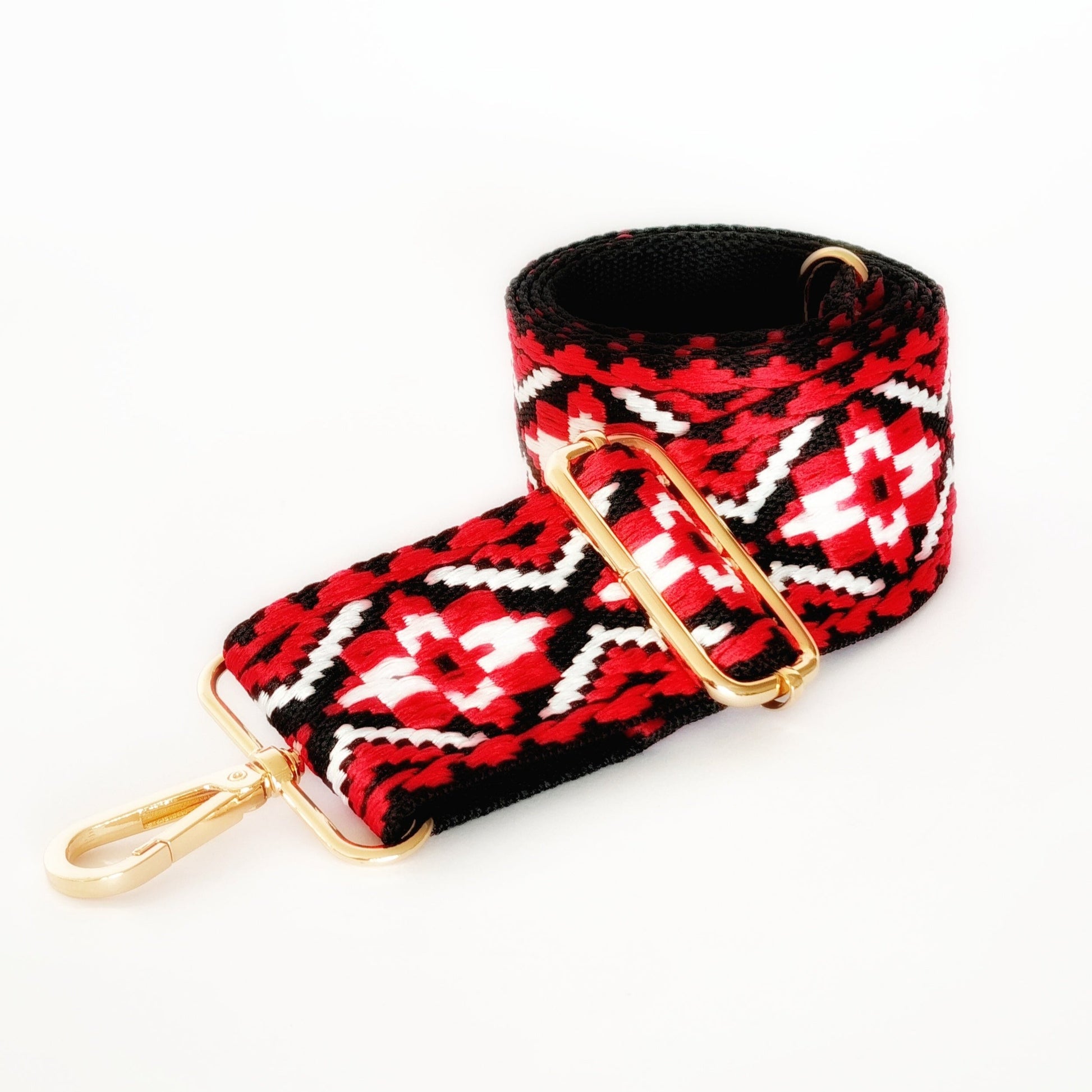 A red and black geometric patterned woven fabric strap with gold hardware and a clip/hook enclosure.