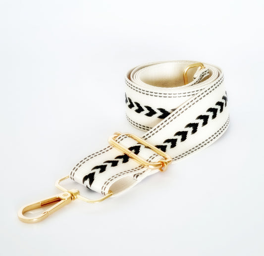 A black and white fabric woven strap with geometric arrow patterns and gold hardware, designed for use with a leather bag.