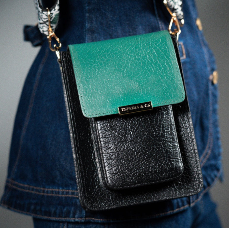 Green and black leather crossbody bag with 'Esperia & Co' branding on a person wearing blue jeans.