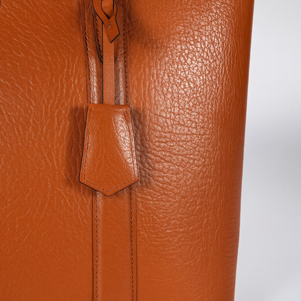 Close-up of a brown leather tote bag with tag