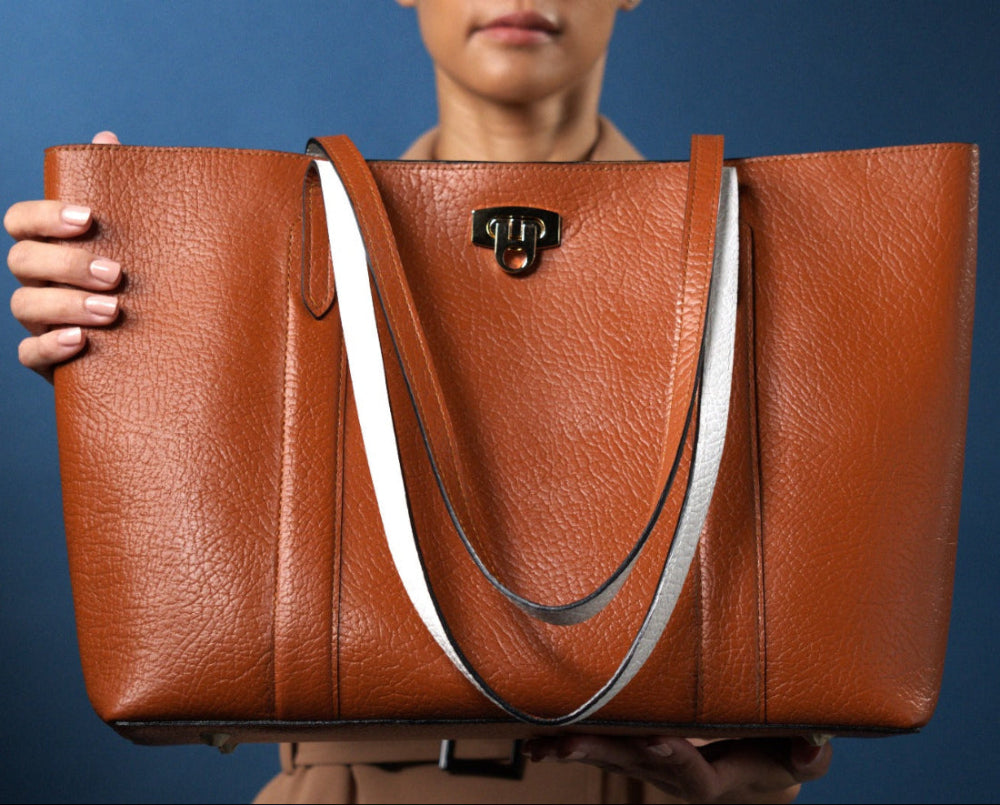 Brown leather tote handbag with white handles held by model