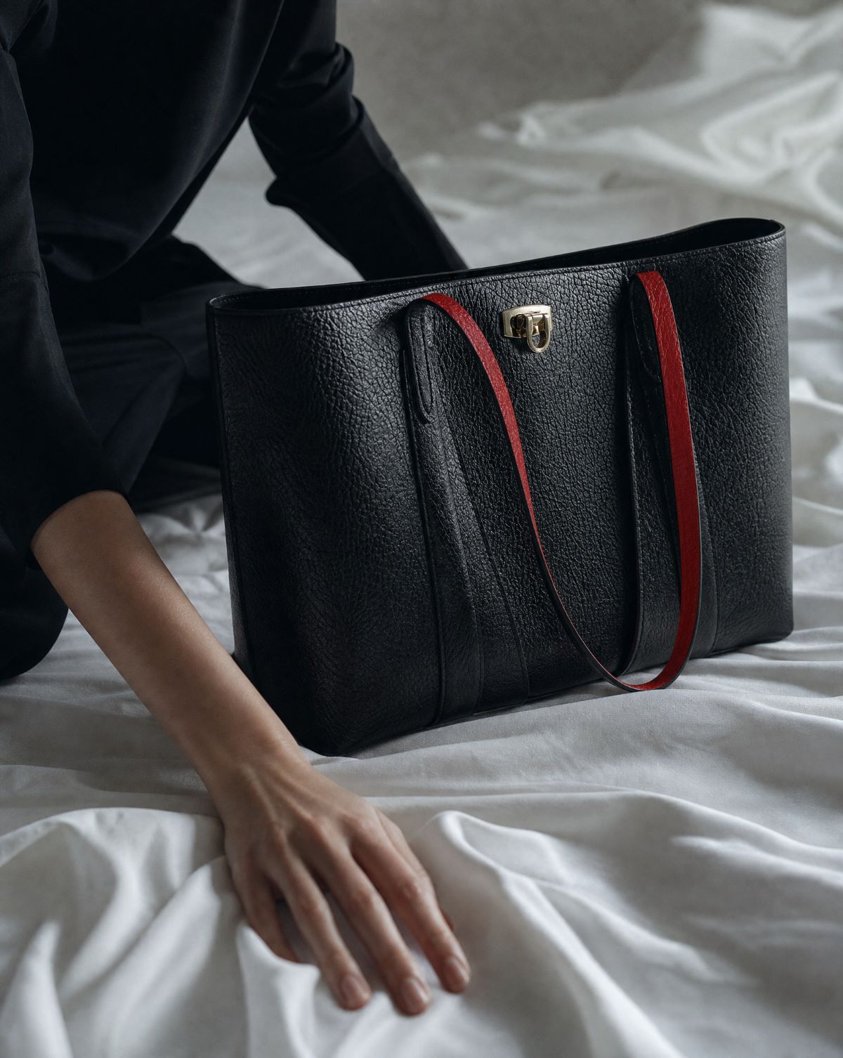 Black handbag with red leather accents with customisable straps