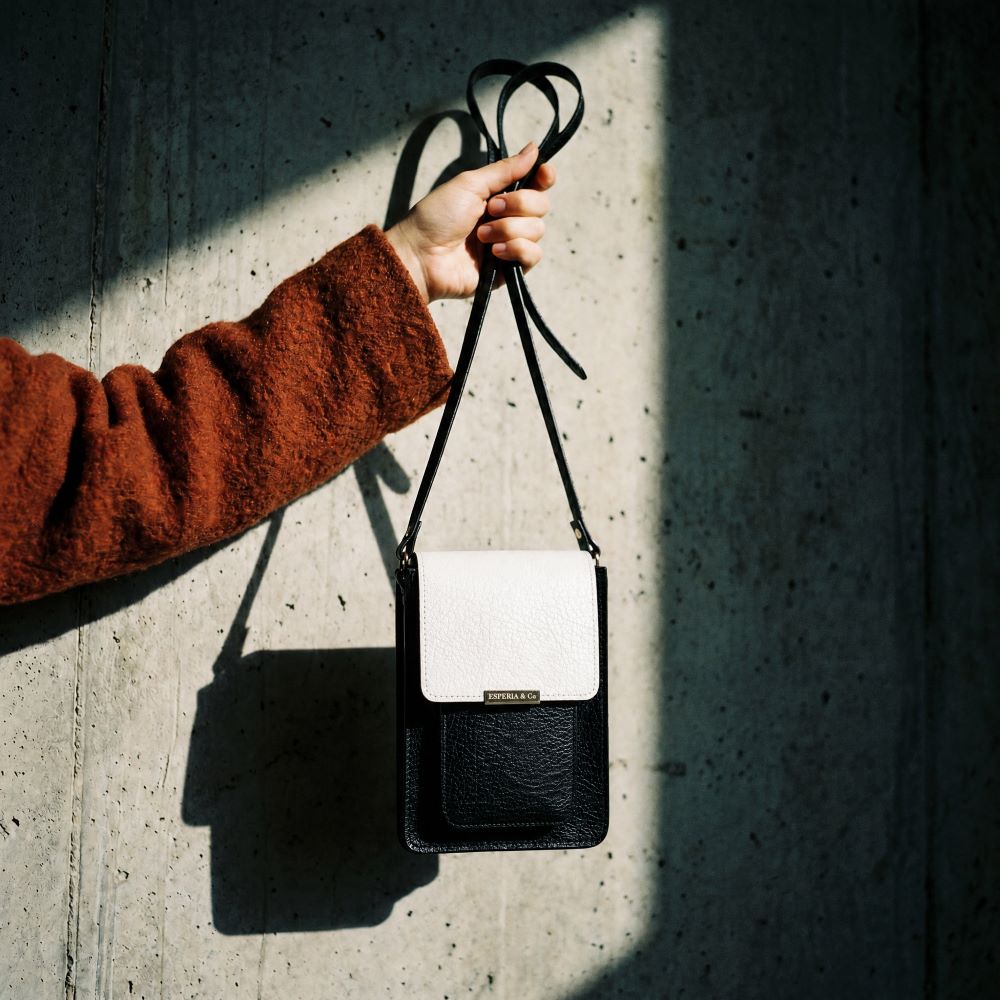 Black and white crossbody bag front view held against a concrete background